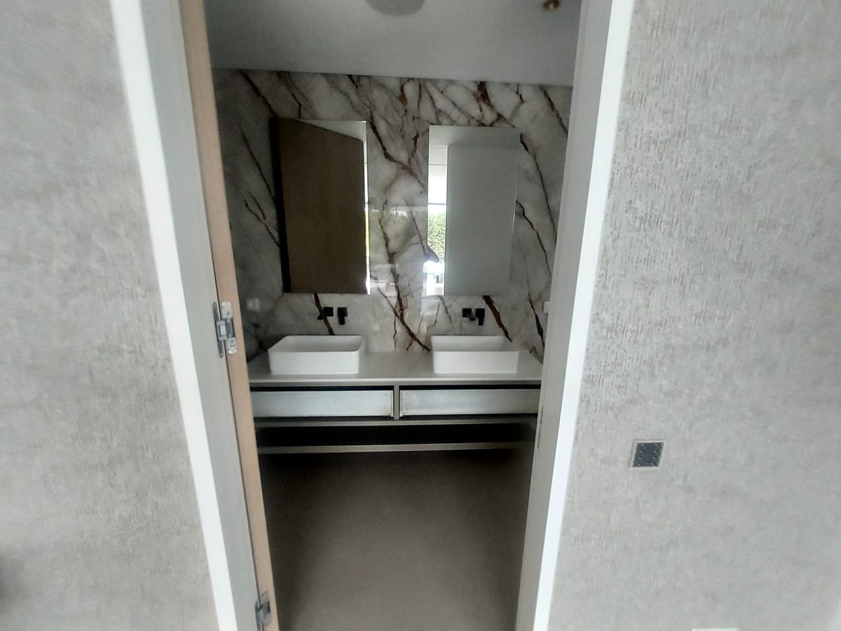 Twin countertop basins on a white floating vanity against dark marble