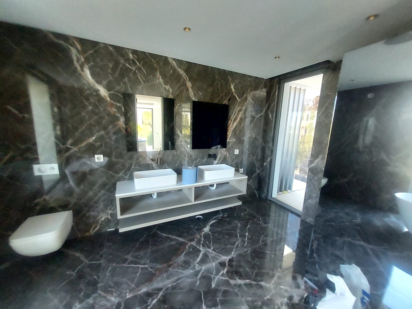 Dark marble bathroom with twin basins, floating vanity and floor-to-ceiling window