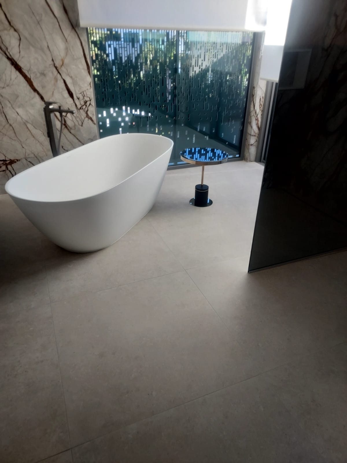 Freestanding bath beside a full-height window in a dark marble bathroom, renovated by M and V Property Services in Kildare