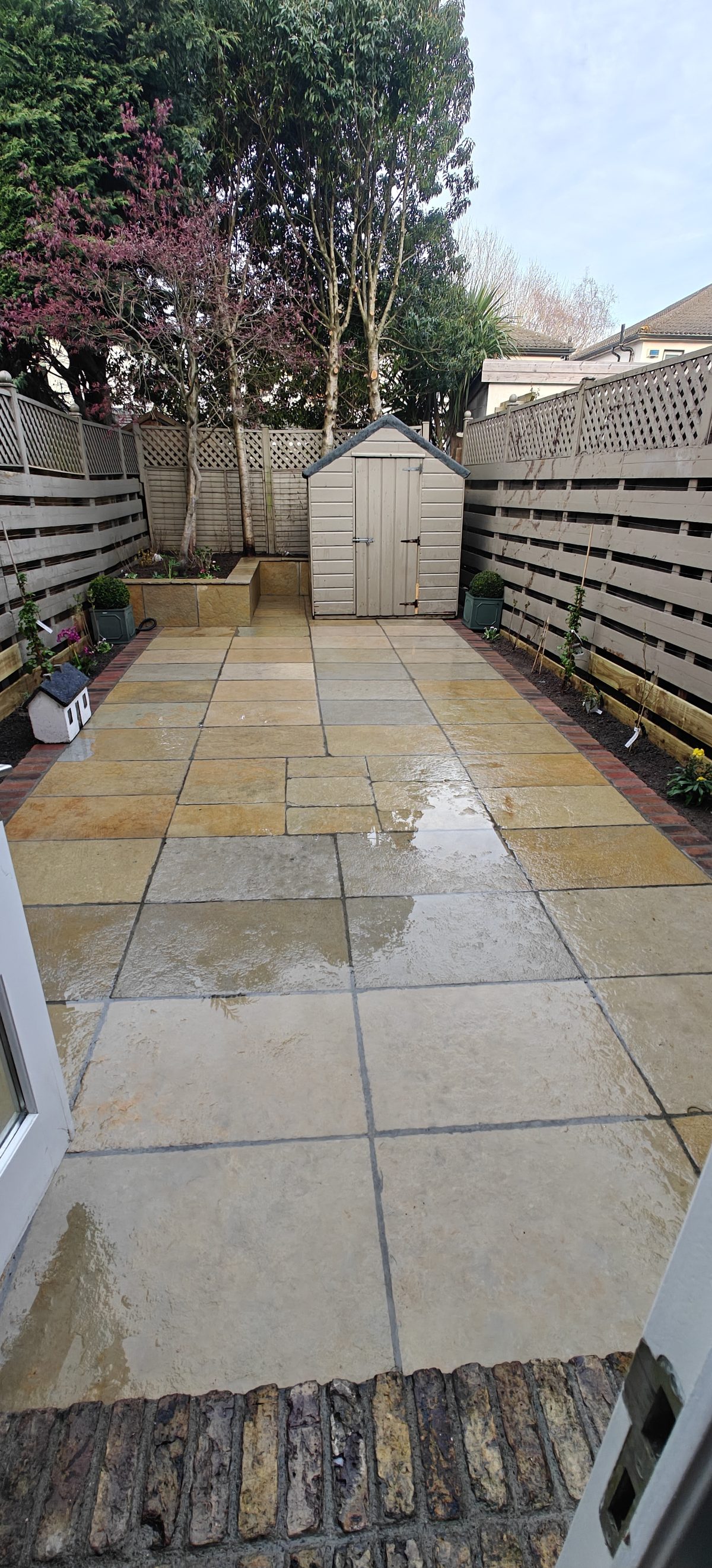 Sandstone patio laid in a walled back garden